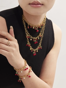 Mannequin portant un ensemble collier et bracelet dorés avec breloques cerise rouge