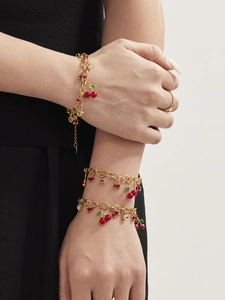 Détail de bracelets cerise plaqués or 18 carats avec perles rouges et zircons au poignet