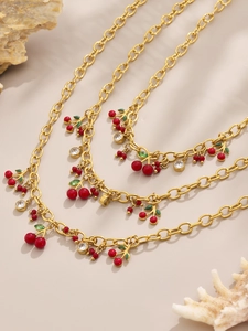 Gros plan d'un collier chaîne dorée avec cerises en émail rouge et accents en zircon