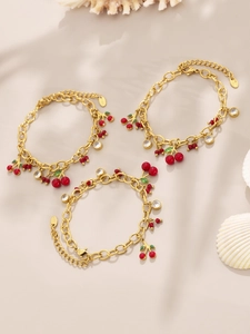 Détail de breloques cerises et zircons sur des bracelets en chaîne plaqués or 18 carats