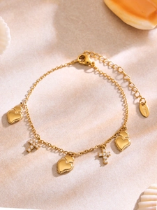 Dettaglio del bracciale dorato in acciaio inossidabile con pendenti a cuore e croce