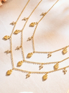 Dettaglio della collana dorata con ciondoli a cuore e croci tempestate di piccoli cristalli