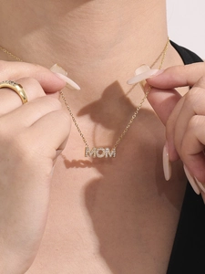 Detail van de MOM-hanger met strassteentjes aan een gouden roestvrijstalen ketting