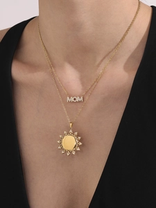 Detail van gelaagde gouden MOM-ketting met zonnebloemhanger bij een vrouwelijk model