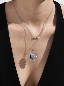 Detail van zilveren MOM-ketting en zonnemedallion met bloemblad schaduweffect op huid