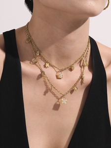 Close-up of double-layered 18K gold chain with padlock, heart, and clover charms