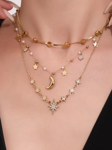 Dettaglio macro di collane a strati in oro 18K con stelle, strass e perle sulla pelle