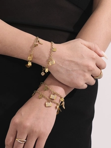 Close-up of gold layered bracelets with heart lock charms and sparkling zircon rings