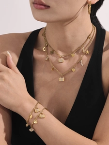 Detail of 18K gold-plated jewelry set with heart and padlock charms on a female model