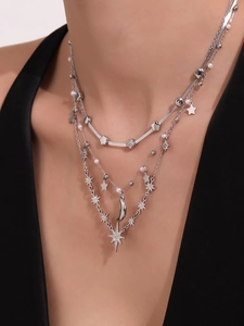Dettaglio di una collana argento a tre strati con ciondoli a stella, luna e cuore su modella