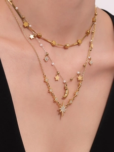 Dettaglio di collane multistrato in oro 18K con stelle, luna e perle lucide