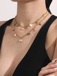 Close-up of double-layer gold necklace with heart, padlock and clover charms