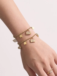 Detail of 18K gold double-layer bracelet with charms like a handbag and clover