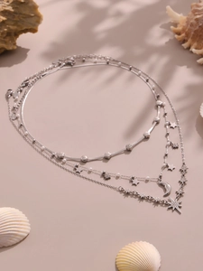Dettaglio di una collana multistrato argentata con ciondoli a stella, luna e perle