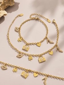 Close-up of gold stainless steel charms including a purse, high heel, and crystal heart
