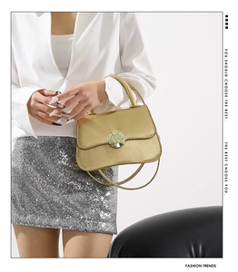 Detail view of a gold fashion handbag with a circular cutout buckle and leather texture