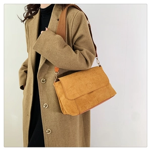 Detail of matte mustard yellow shoulder bag with wide strap and golden metal hooks