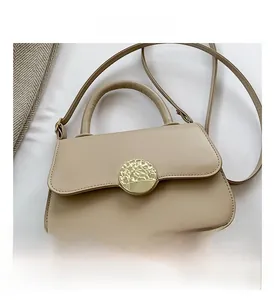 Detail of beige faux leather handbag featuring a textured round gold magnetic clasp