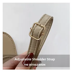 Detail of adjustable leather shoulder strap with a gold square buckle on beige handbag