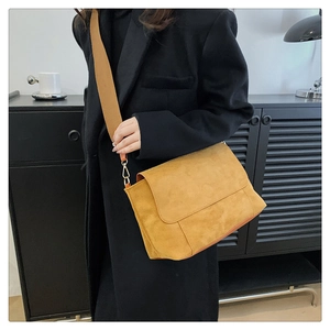 Detail of ginger suede crossbody bag with wide knit strap and golden hardware