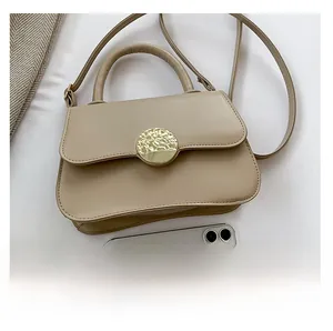 Top view of beige leather handbag with gold metal buckle showing size compared to a phone