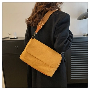 Detail of yellow frosted suede messenger bag with textured flap and gold metal hardware