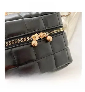 Détail du sac seau en cuir matelassé noir avec double fermeture éclair dorée élégante