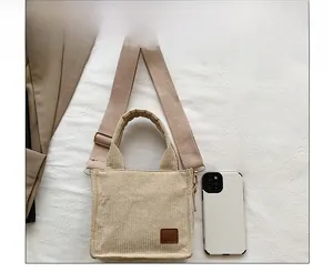 Nahaufnahme der beigen Cordstruktur und des braunen Lederaufnähers der Tasche