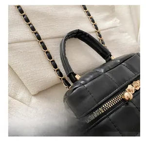 Détail du sac à main noir matelassé avec finitions dorées et bandoulière en chaîne