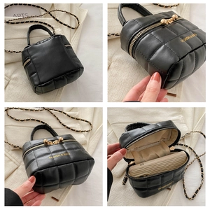 Détail du sac seau noir matelassé avec fermeture éclair dorée et bandoulière chaîne