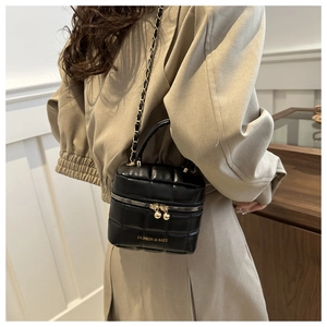 Détail du sac seau matelassé noir avec chaîne dorée et design boîte de toilette