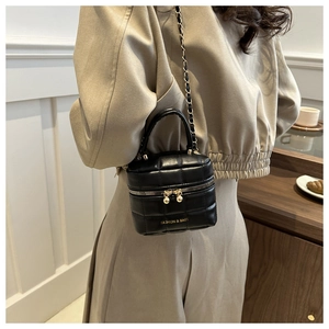 Sac seau en cuir noir matelassé avec chaîne dorée porté par un mannequin pour l'échelle
