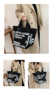 Detail of black canvas tote bag showing large white North Shore Hawaii typography print