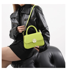 Close-up of neon green leather handbag with unique tree-shaped metal buckle detail