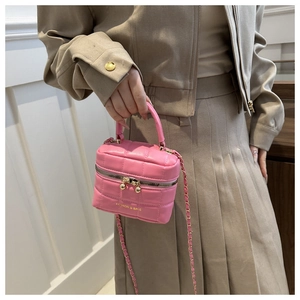 Détail du sac seau rose matelassé avec bandoulière chaîne dorée et lettrage mode