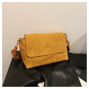 Detail of mustard yellow suede messenger bag with brown strap and metal hook closure