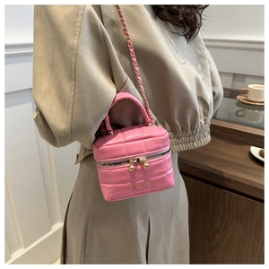 Gros plan d'un sac seau rose matelassé avec bandoulière chaîne porté par un modèle