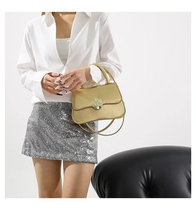 Detail of gold handbag featuring a metallic tree-of-life circular buckle and round handle