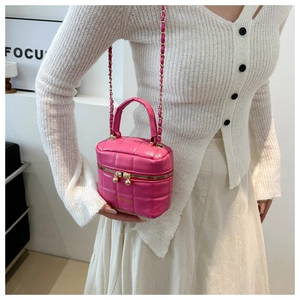 Détail du sac seau rose matelassé avec chaîne dorée et double fermeture à boules dorées