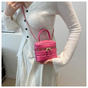 Gros plan d'un sac seau rose matelassé avec bandoulière chaîne et poignée sur un modèle