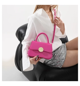Detail of rose pink leather crossbody bag with round gold buckle on white shirt model