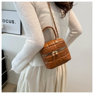 Détail d'un sac seau marron matelassé avec bandoulière chaîne dorée et double zip
