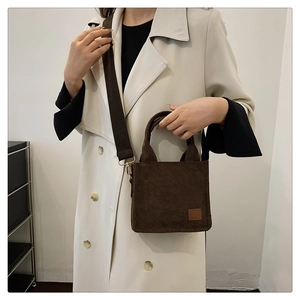 Detail der dunkelbraunen Cord-Handtasche mit Strukturstoff und gewebtem Schultergurt