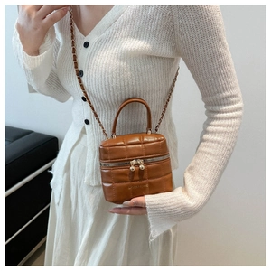 Détail d'un sac à main marron en similicuir matelassé avec chaîne et poignée supérieure