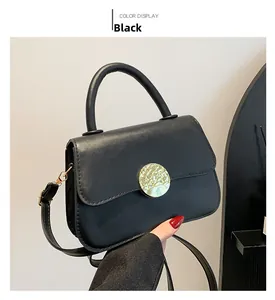 Detail of minimalist black crossbody bag with a hammered gold metal clasp and strap