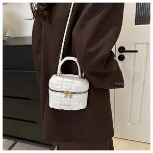 Sac seau matelassé blanc pour femme porté par un mannequin dans un décor minimaliste
