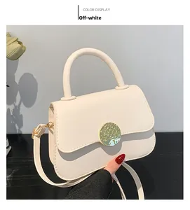 Close-up of cream white handbag featuring a textured gold round buckle and neat stitching
