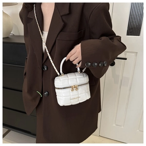Gros plan d'un sac bandoulière en similicuir blanc mat avec chaîne dorée chic