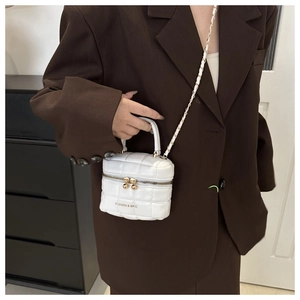 Gros plan du sac seau blanc matelassé avec chaîne dorée et fermeture éclair élégante