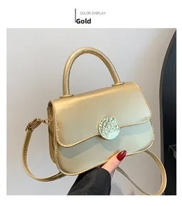 Detail of gold metallic handbag with textured round swivel lock and slim shoulder strap